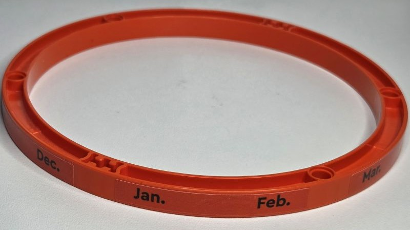 Lego Technic, Liftarm, Modified Frame Round Thick 15 x 15 Open Center with Black 'Jan. Feb. Mar. Apr. May June July Aug. Sept. Oct. Nov. Dec.' Pattern (Stickers) - Set 42179 / Reddish Orange