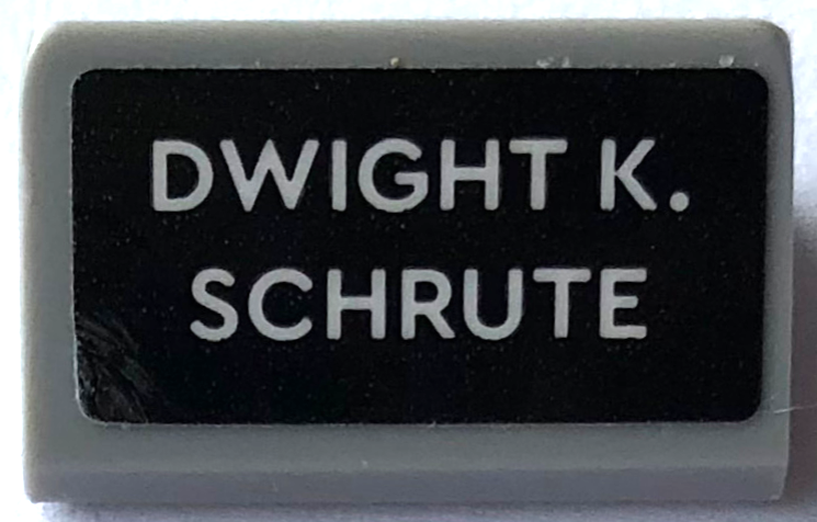 Lego Slope 30 1 x 2 x 2/3 with 'DWIGHT K. SCHRUTE' Pattern (Sticker) - Set 21336 / Light Bluish Gray