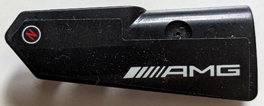 Lego Technic, Panel Fairing #22 Very Small Smooth, Side A with White 'AMG' Logo and Red Capital Letter N in Circle Pattern (Sticker) - Set 42165 / Black