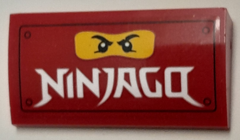 Lego Slope, Curved 2 x 4 x 2/3 with Bottom Tubes with Yellow Minifigure Face and White 'NINJAGO' Pattern (Sticker) - Set 40429 / Red