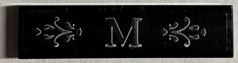 Lego Tile 1 x 4 with Silver Letter M and Ornate Scrollwork Pattern Background (Sticker) - Set 21330 / Black