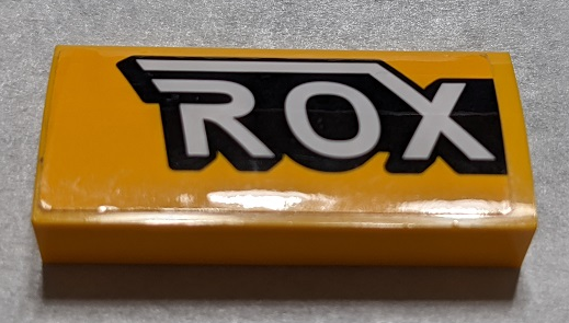 Lego Slope, Curved 2 x 4 x 2/3 with Bottom Tubes with Black and White 'ROX' Pattern Side A (Sticker) - Set 76067 / Bright Light Orange