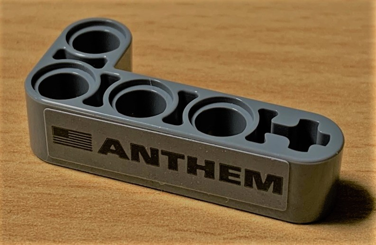 Lego Technic, Liftarm, Modified Bent Thick L-Shape 2 x 4 with 'ANTHEM' and Black United States of America (USA) Flag Pattern (Sticker) - Set 42078 / Dark Bluish Gray