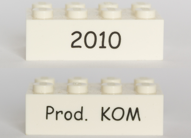 Lego Brick 2 x 4 with Black '2010' and 'Prod. KOM' Pattern on Opposite Sides (Kornmarken Factory Tour)
